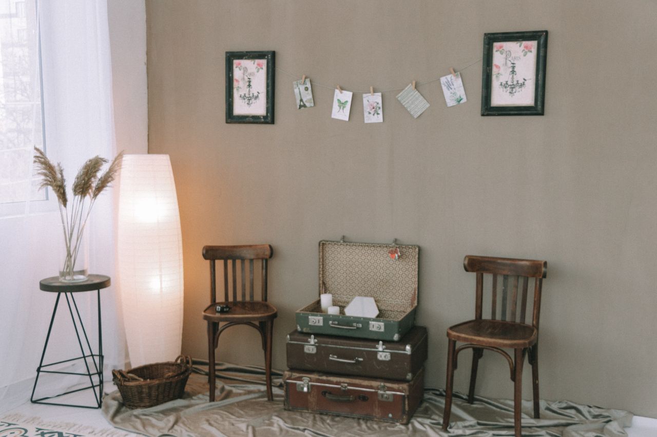 Cozy vintage room with wooden chairs, stacked luggage, and decorative wall art.